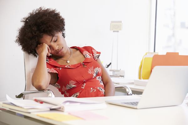 Image of woman who fell asleep at her desk which is a symptom of sleep apnea.